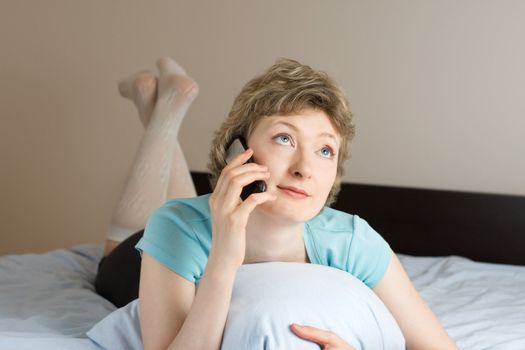 young woman with mobile phone on a bed, shallow DOF, focus on eyes