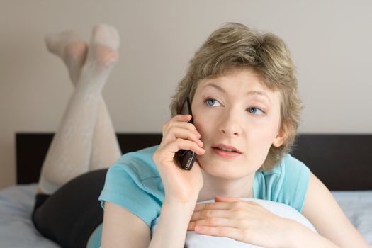 young woman with mobile phone on a bed, shallow DOF, focus on eyes