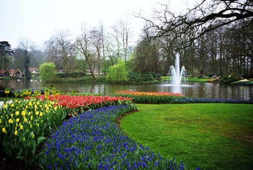 A fountain decorates a lake surrounded by spring tulips in Keukenhof Gardens, Lisse, The Netherlands.