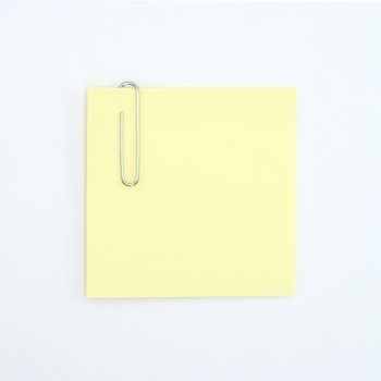 A close up of a paperclip on a sticky note shot against a white background.