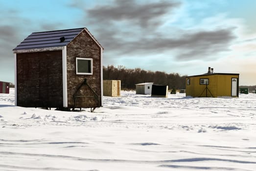 Temporary shacks used for ice fishing situated on the frozen "Red River" in Manitoba.