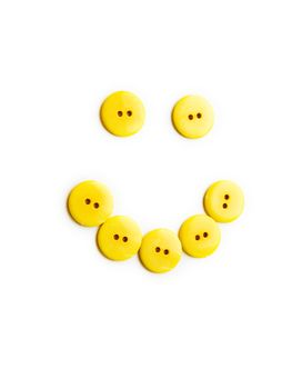 Funny smile of big yellow buttons over white