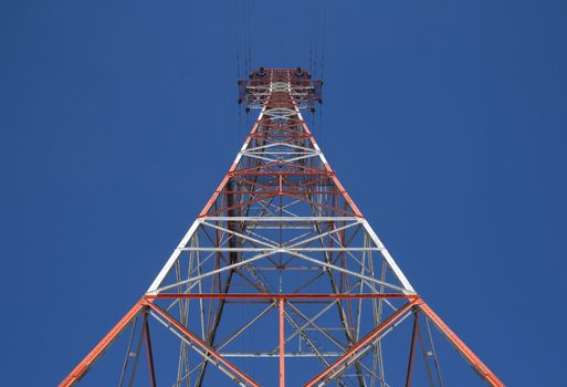 Red triangular high voltage power tower in the blue sky.