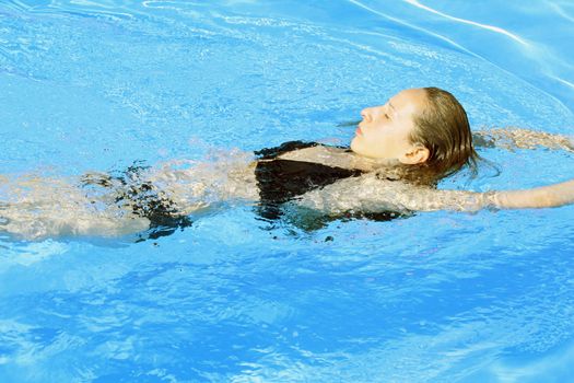 woman takes a sunbath in the swimming pool