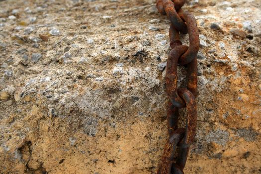 Detail of a rusty chain on a stone.