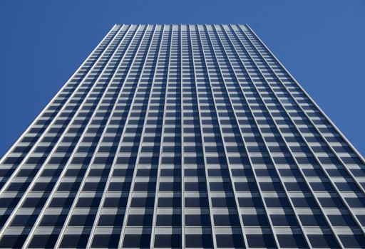 Perspective view of the gray office building against the blue sky.