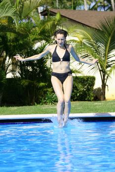 woman jumping in the swimming pool by hotel