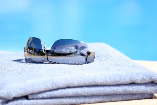 sunglasses on towel by the pool