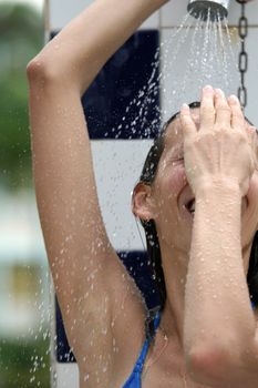 tanned woman in bikini at summer shower on the beach