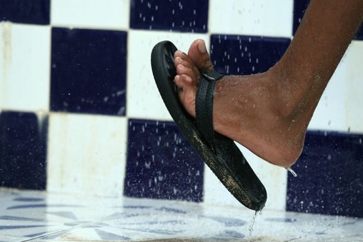 tanned foot with flip-flops under the shower