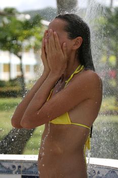 woman in bikini at summer shower on the beach