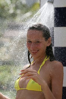 tanned woman in bikini taking shower on the beach