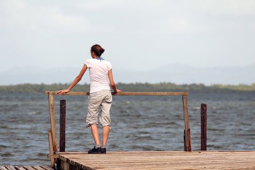 woman standing on the wooden pier at caribbean sea
