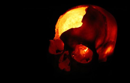Burning skull - Old broken skull against black background with inner flame
