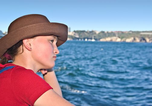 a teenage girl looks wistfully off to sea 
