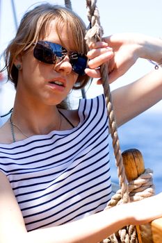 Beautiful young woman in sunglasses sailing on a boat