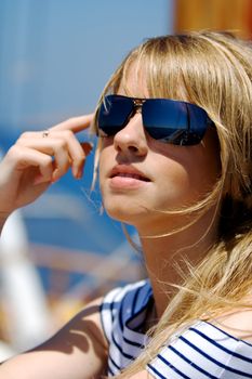 Beautiful young woman in sunglasses sailing on a boat