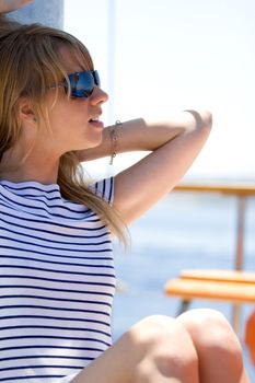 Beautiful young woman in sunglasses sailing on a boat