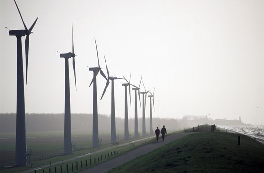 Couple walking by a windpark on a misty morning.