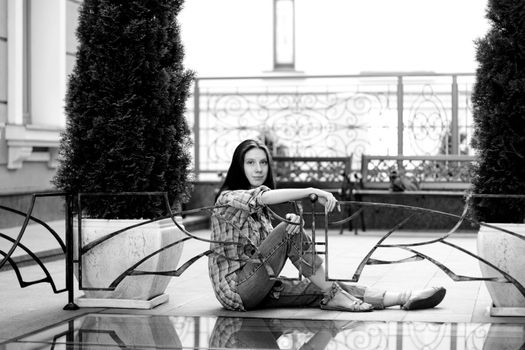 Girl sitting on floor near fence 
