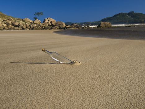 A bottle with a message inside is buried on the beach.