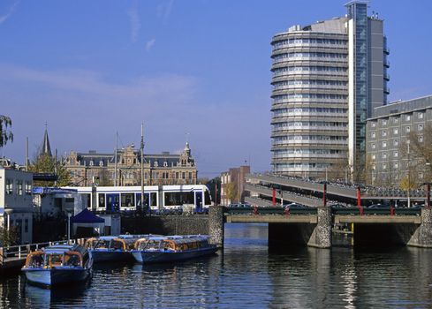 Boats on a canal in Amsterdam, the Netherlands with a tram and bikes in background.