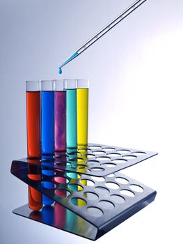 Close up of test tubes filled with color liquids and a pipette.