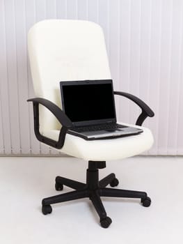 Black laptop sits in a leather chair for the manager