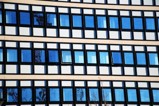 A photograph of an example of modern architecture, with opposing buildings, the blue sky, and a construction crane in reflection.