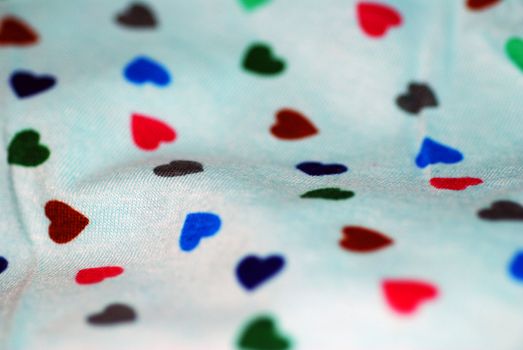 A close up photograph of fabric with small hearts in different colours.