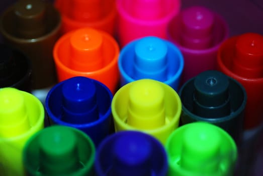 A macro photograph of a group of brightly colored pen lids