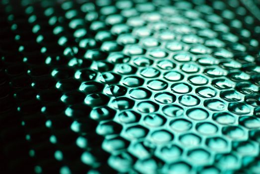 A dramatically lit photograph of metallic green bubble wrap