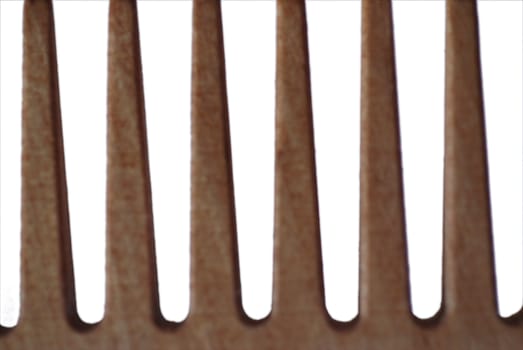 An extreme close up photograph of the teeth of a wooden comb