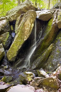 A beautiful waterfall flowing through some large rocks in the woods.