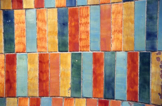 Grungy multi-coloured tiles on a wall.