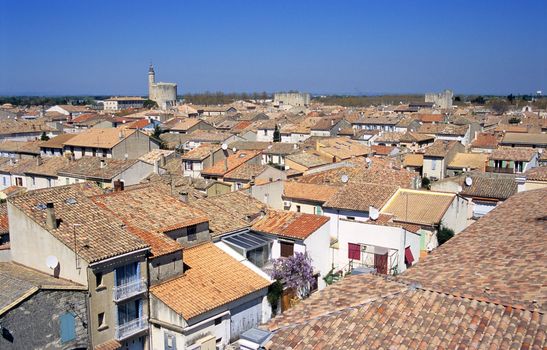 Terra Cotta Tile roofs are covered with skylights and satelite dishes in Aigues-Mortes. The city walls and the Tour de Constance are visible in the distance.