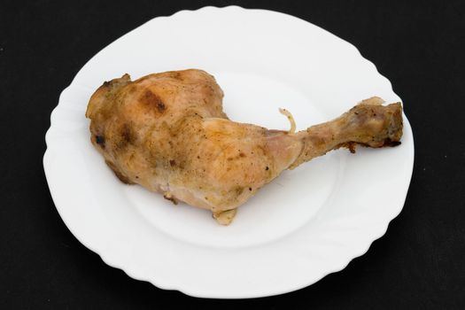 The fried part of a chicken on a white plate on a black background