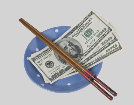 banknotes and chopsticks on a plate isolated