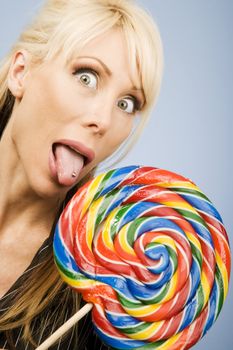 Woman with a pierced tongue licking a big colorful lollipop