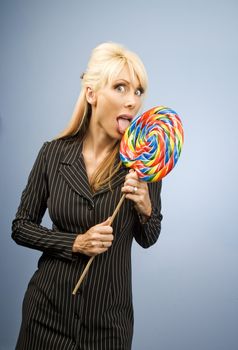Woman with a pierced tongue licking a big colorful lollipop