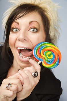 Portrait of a creative businesswoman with wild hair licking a lollipop