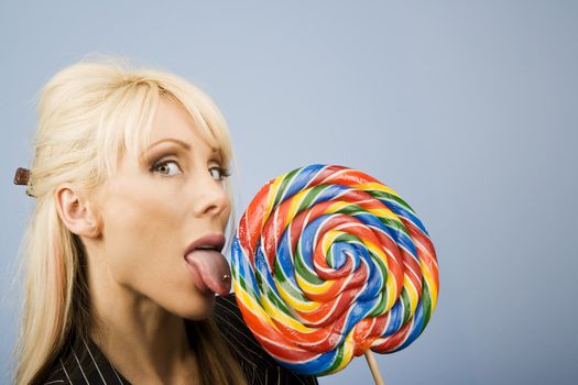 Woman with a pierced tongue licking a big colorful lollipop