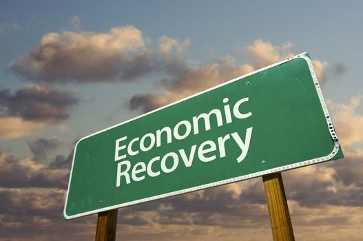 Economic Recovery Green Road Sign with dramatic clouds and sky.