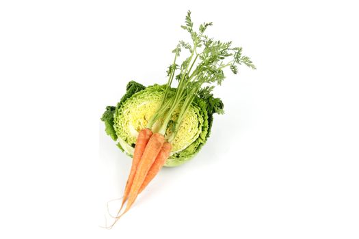 Half a raw green cabbage with a bunch of raw carrots on a reflective white background