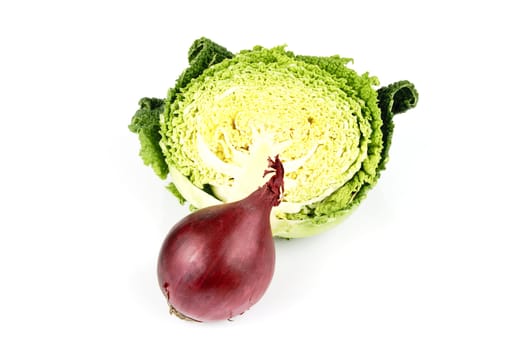 Half a raw green cabbage with a single raw red onion  on a reflective white background