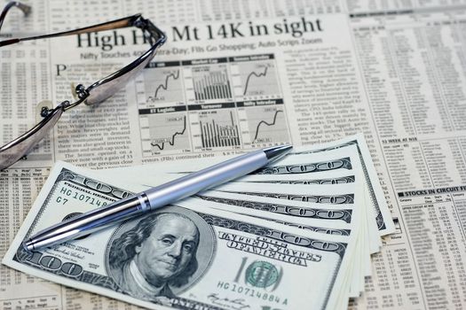 Money Investments and Stocks in a newspaper with pen and dollar