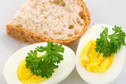 Cooked eggs decorated with parsley and a slice of whole grain bread.