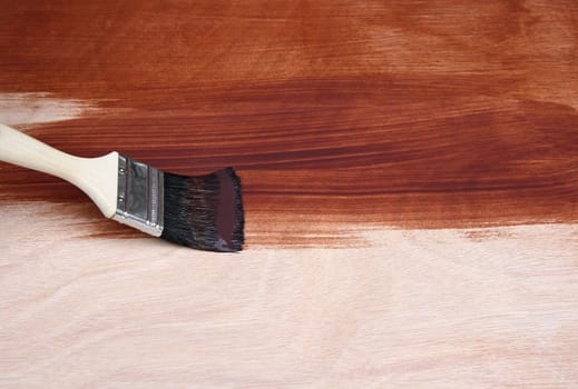 Painting a wooden surface with a paint brush.