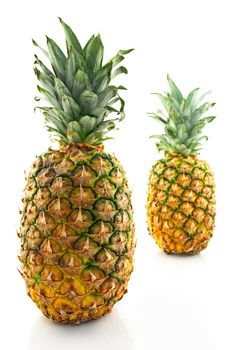 Two ripe pineapples on white background, focus on the closest one.