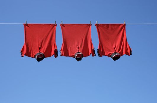 Laundry, three red t-shirts on a clothes-line.